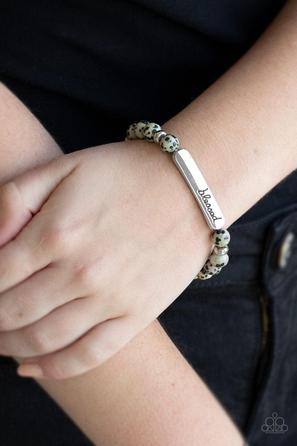 Paparazzi Accessories Simply Blessed - Black A collection of speckled stones, dainty silver beads, and a silver plate stamped with the inspirational word, "blessed", are threaded along a stretchy band around the wrist for a seasonal look. Jewelry