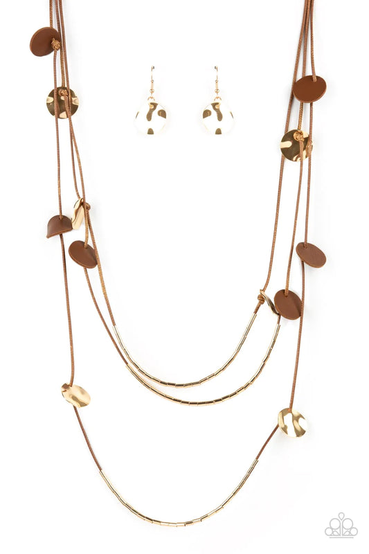 Paparazzi Accessories Alluring Luxe - Brown Shining wavy gold discs and brown leather discs adorn a trio of lengthened subtly shimmering brown cords. Rows of dainty gold cylinders are threaded along the bottom of each cord adding luxurious allure to the p