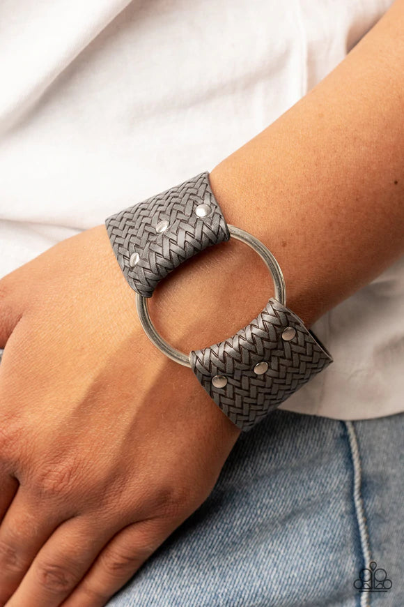 Paparazzi Accessories Aspiring Adventurist - Silver An oversized silver ring is studded in place across the center of the wrist between two pieces of textured gray leather bands, resulting in a rustic centerpiece around the wrist. Features an adjustable s