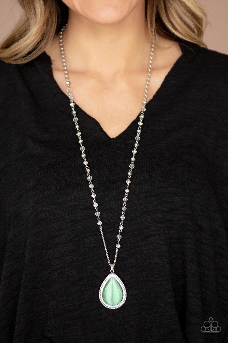 Paparazzi Accessories Fashion Flaunt - Green Encrusted in rows of glassy white rhinestones, an imperfect silver teardrop frame is encrusted in a glowing green cat's eye stone. The ethereal pendant swings from the bottom of a lengthened silver chain dotted