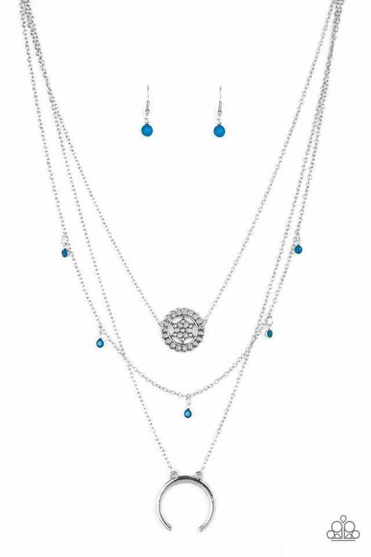Paparazzi Accessories Lunar Lotus - Blue A silver floral frame swings from the uppermost chain, above a strand of faceted blue beads swinging from a shimmery silver chain. A silver crescent frame swings from the lowermost chain, creating whimsical layers