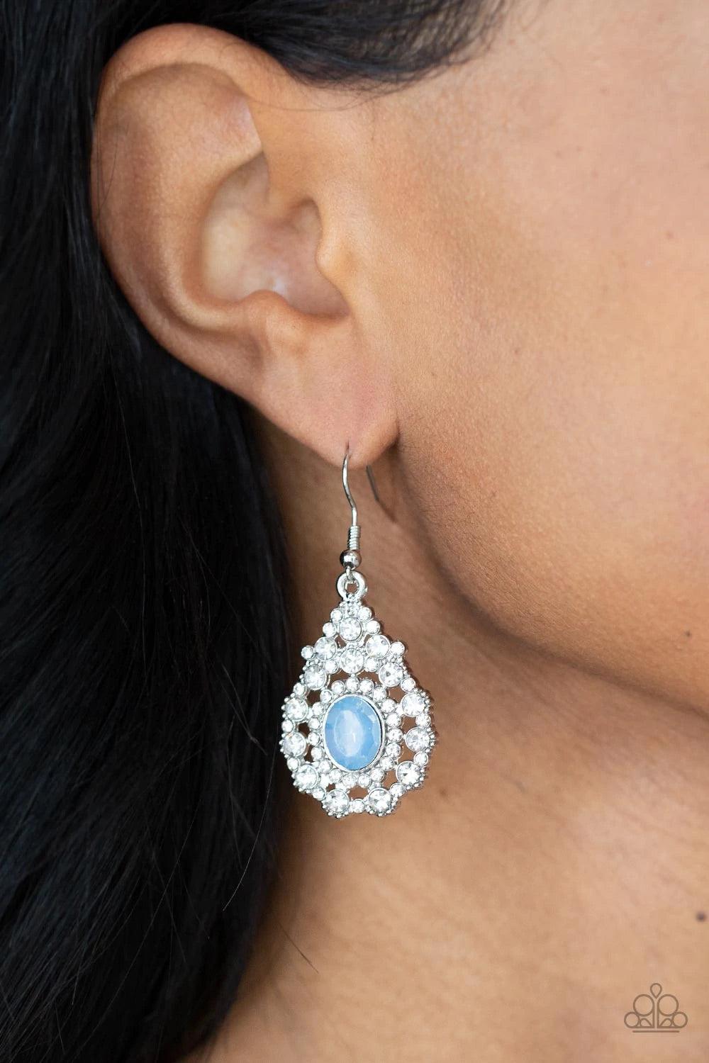Paparazzi Accessories Celestial Charmer - Blue Bordered in a ring of dainty white rhinestones, an opalescent blue gem adorns the center of a teardrop frame radiating with glassy white rhinestones for an ethereally elegant look. Earring attaches to a stand