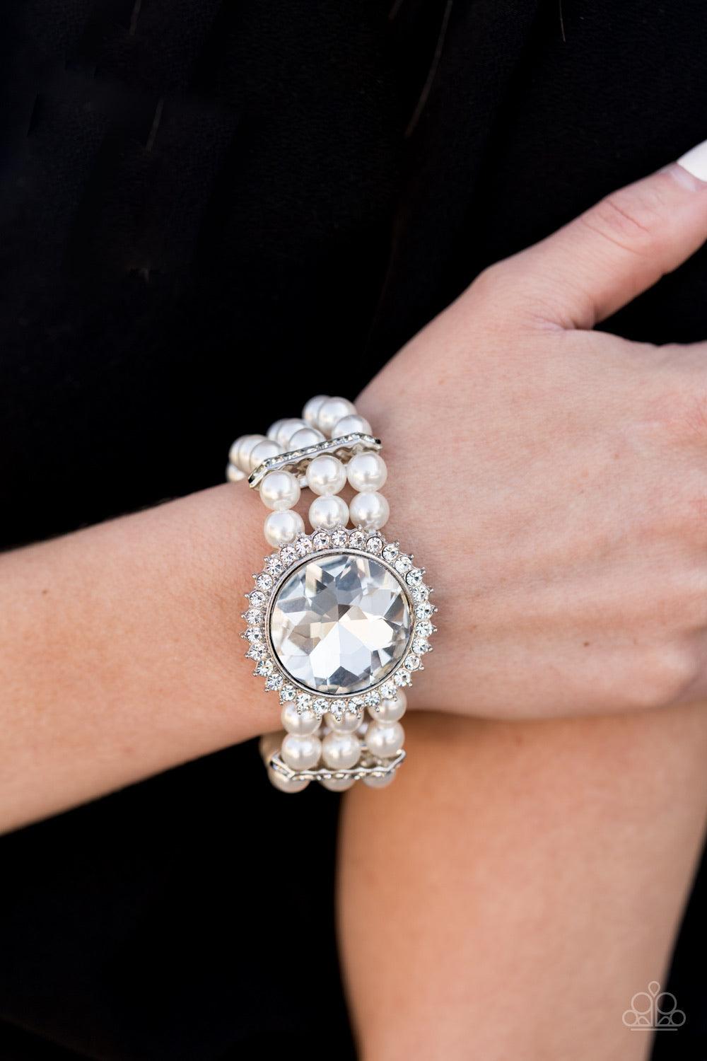 Paparazzi Accessories Speechless Sparkle - White Threaded along stretchy bands, strands of pearly white beads are held in place with white rhinestone encrusted fittings around the wrist. Bedazzled in a ring of glassy white rhinestones, a dramatically over