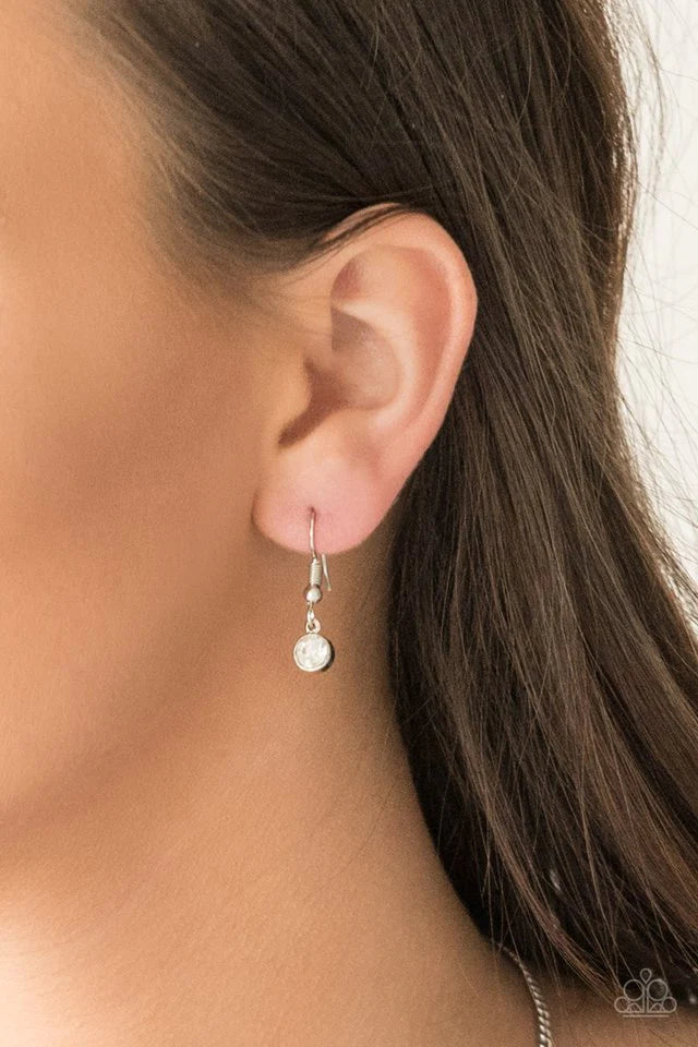 Paparazzi Accessories Chicly Centered - White Brushed in a gritty antiqued finish, a rippling silver frame flares from a white rhinestone encrusted center for an edgy look. Features an adjustable clasp closure. Sold as one individual necklace. Includes on