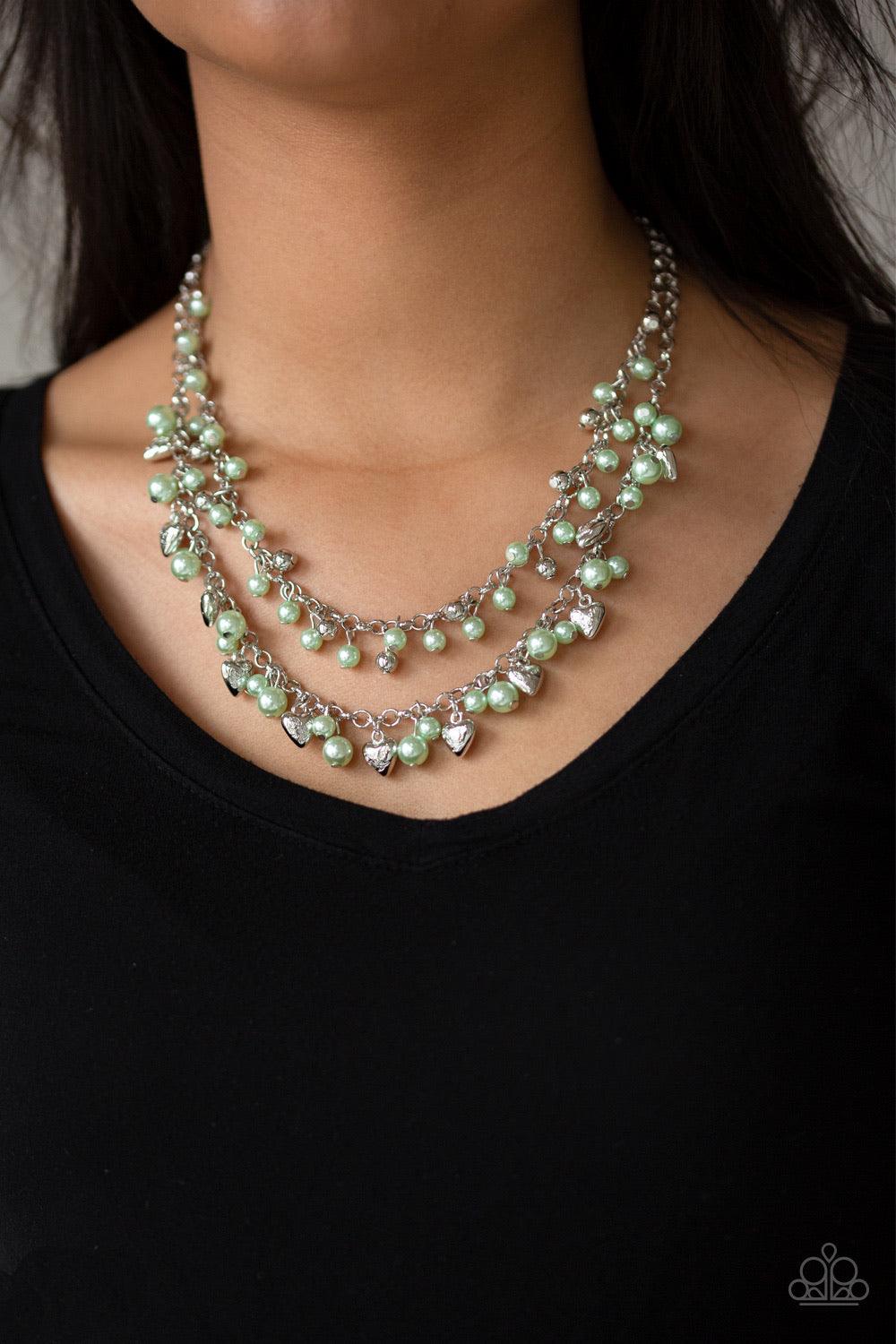 Paparazzi Accessories Kindhearted Heart - Green A collection of shiny silver beads and pearly green beads cascade from the bottoms of two layered silver chains. Stamped in the word, "Love", floral heart charms dangle from the lowermost chain, creating a f