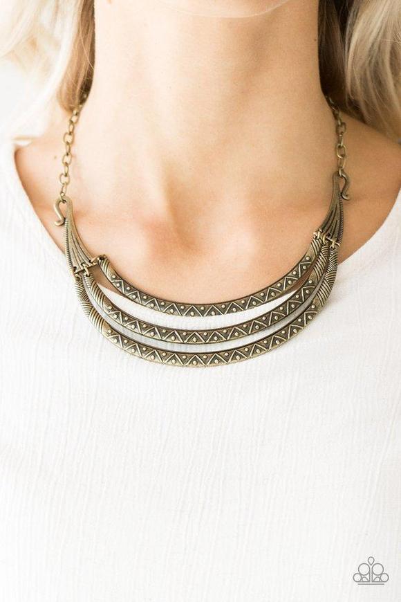 Paparazzi Accessories Primal Princess - Brass Embossed in zigzagging patterns, brass crescents swing from two ornate brass plates for a tribal inspired look. Dotted with studded textures, the antiqued pendants delicately stack below the collar for a bold