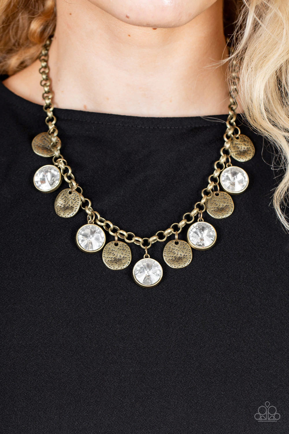 Paparazzi Accessories Spot On Sparkle - Brass A blinding collection of hammered brass discs and oversized white gems swing from the bottom of a bold brass chain, creating noise-making sparkle below the collar. Features an adjustable clasp closure. Sold as
