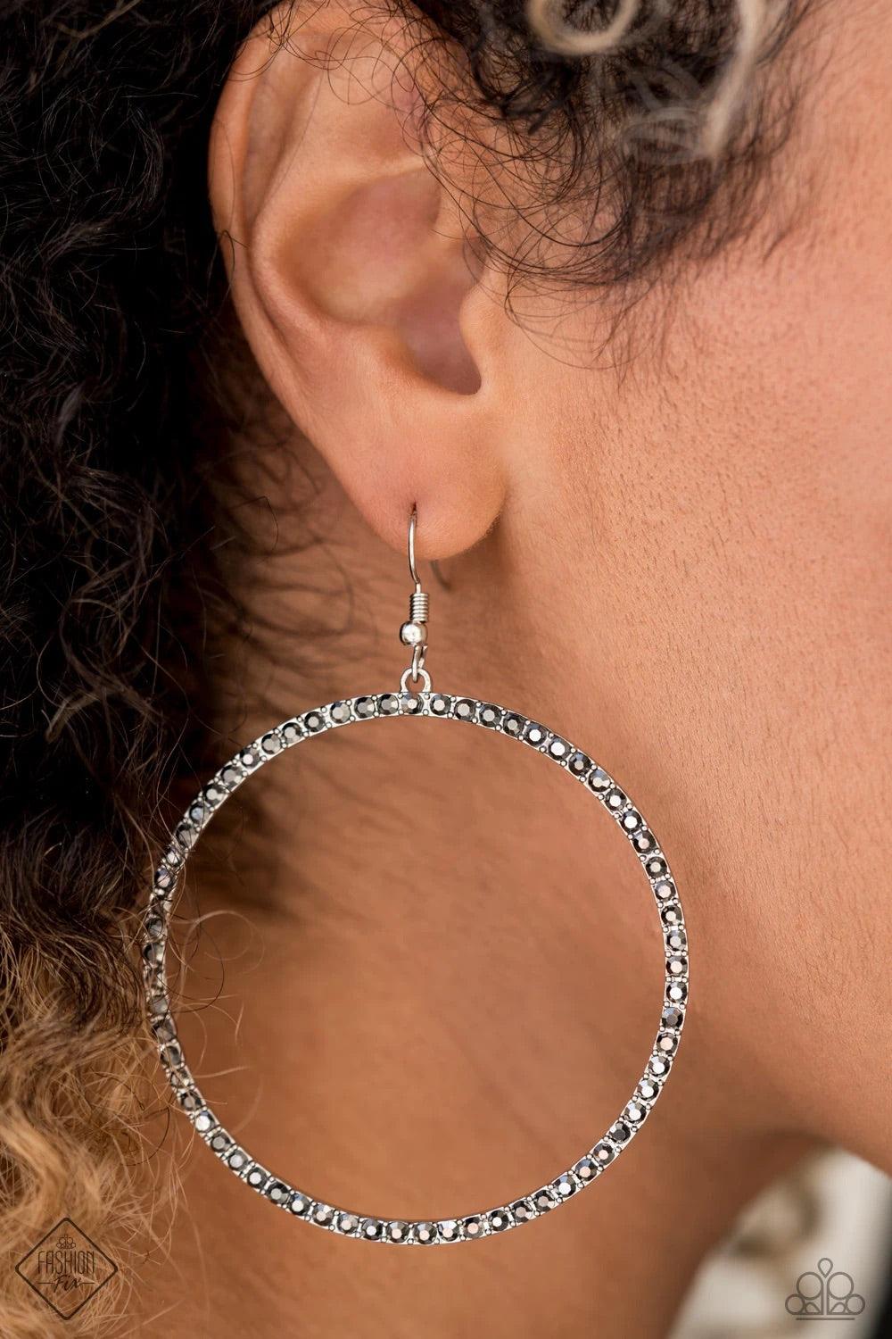 Paparazzi Accessories Wide Curves Ahead - Silver Encrusted in smoky hematite rhinestones, a dramatically oversized hoop swings from the ear for an exaggerated effect. Earring attaches to a standard fishhook fitting. Hoop measures approximately 2 1/4" in d