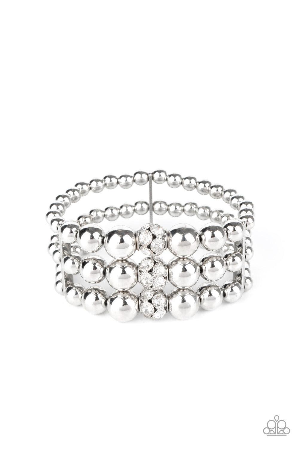 Paparazzi Accessories Icing On The Top - White Held together with dainty silver fittings, strands of silver beads are threaded along stretchy bands around the wrist. Glassy white rhinestone encrusted beads adorn the center, adding a splash of sparkle to t