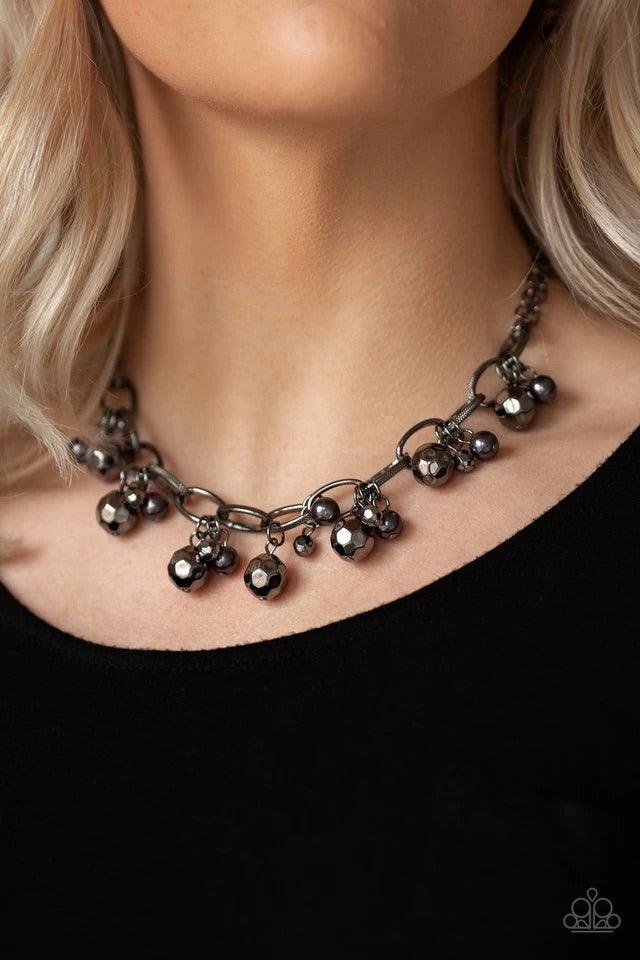 Paparazzi Accessories Malibu Movement - Black Varying in size, a collection of faceted gunmetal and pearly gunmetal beads swings from a bold gunmetal chain, creating a whimsical metallic fringe below the collar. Features an adjustable clasp closure. Jewel