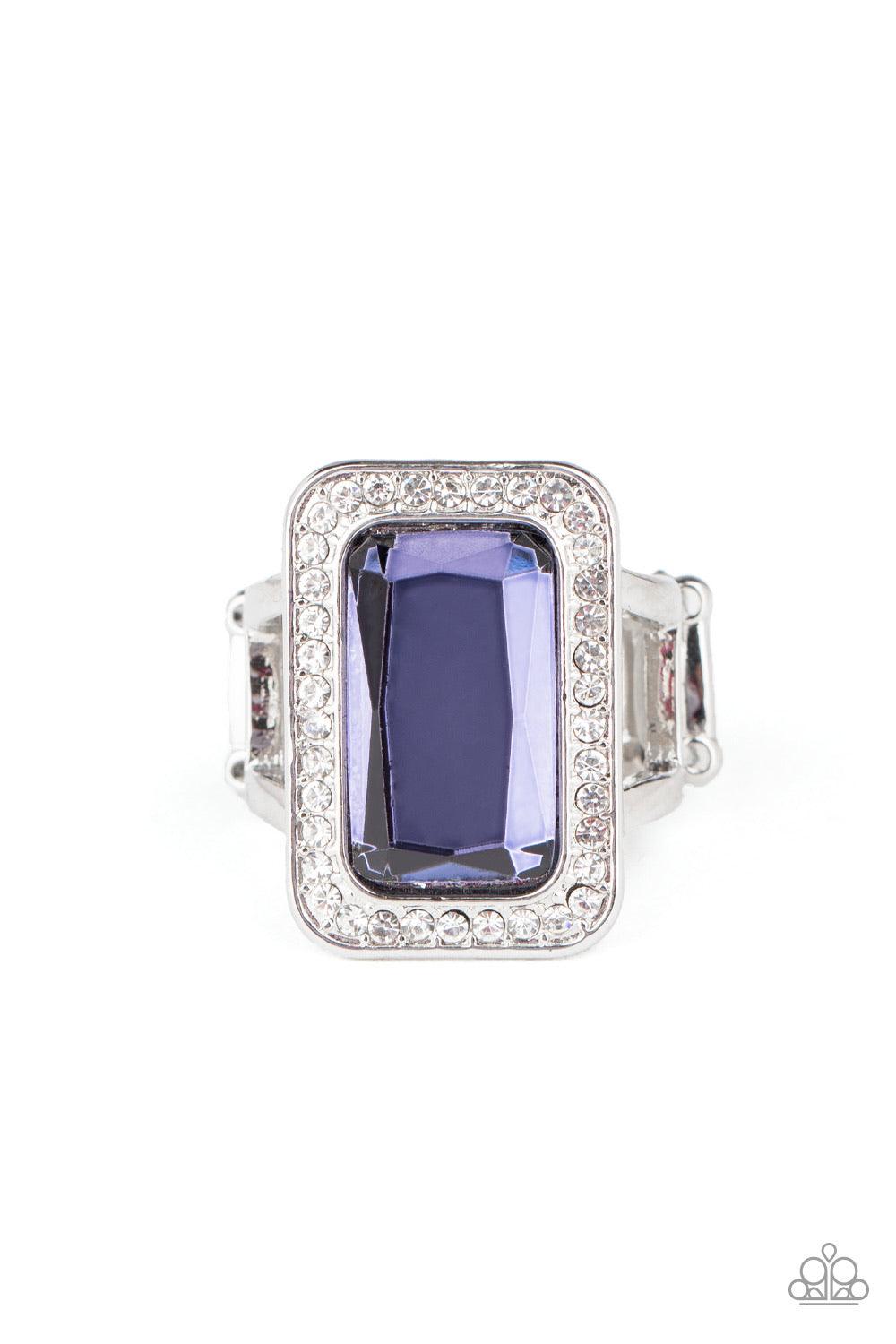 Paparazzi Accessories Crown Jubilee - Purple Featuring a regal emerald style cut, an oversized purple gem is bordered by a silver frame encrusted in glassy white rhinestones for a glamorous look. Features a stretchy a band for a flexible fit. Sold as one