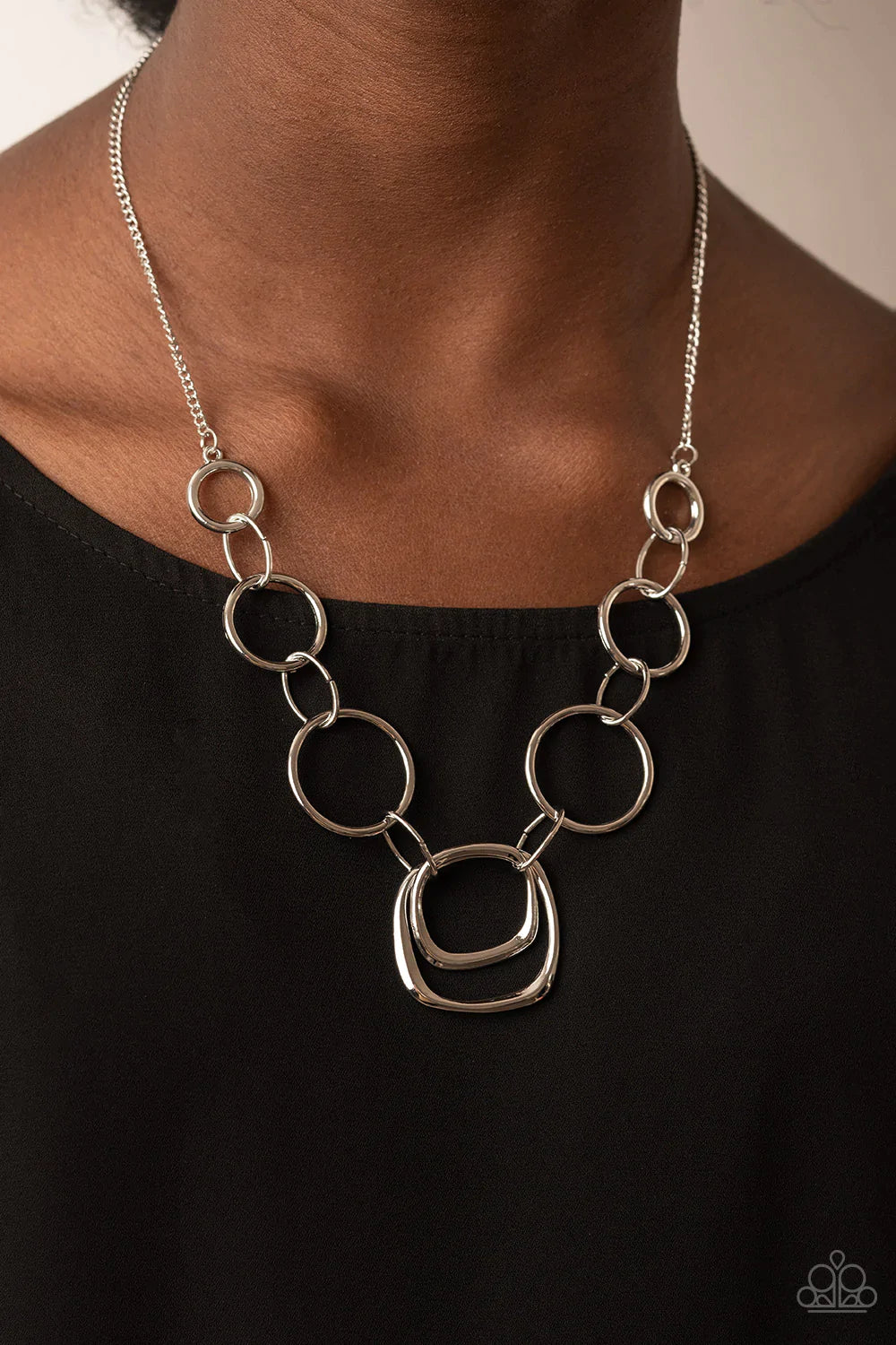 Paparazzi Accessories Linked Up Luminosity - Silver A mismatched collection of silver rings and asymmetrical silver hoops delicately links below the collar, resulting in a modern industrial display. Features an adjustable clasp closure. Sold as one indivi