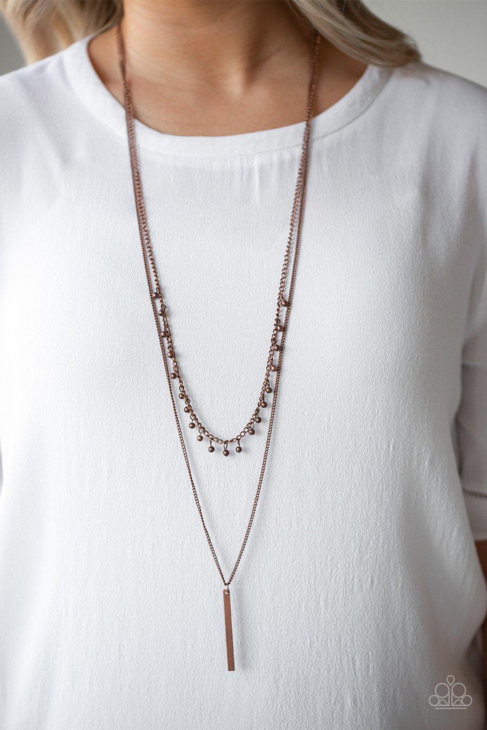 Paparazzi Accessories Keep Your Eye On The Pendulum - Copper Two mismatched copper chains layer down the chest. Dainty copper beads dangle from the bottom of the uppermost chain, while a rectangular pendulum-like pendant swings from the lowermost chain fo