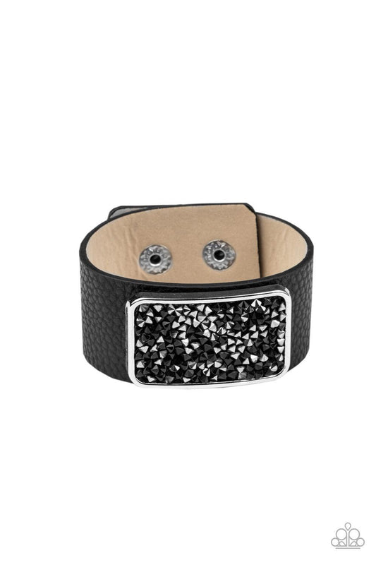 Paparazzi Accessories Interstellar Shimmer - Black A collision of black and hematite rhinestones collect inside a silver rectangular frame that is studded in place in the center of a thick black leather band, creating a sparkling statement piece around th