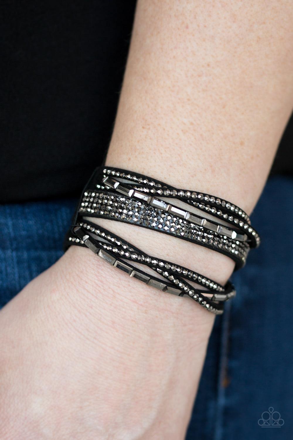 Paparazzi Accessories Tough Girl Glamour - Black Featuring edgy emerald and classic style cuts, glittery hematite rhinestones are encrusted along crisscrossing strands of black suede for a fierce one-of-a-kind look. Features an adjustable snap closure. Je