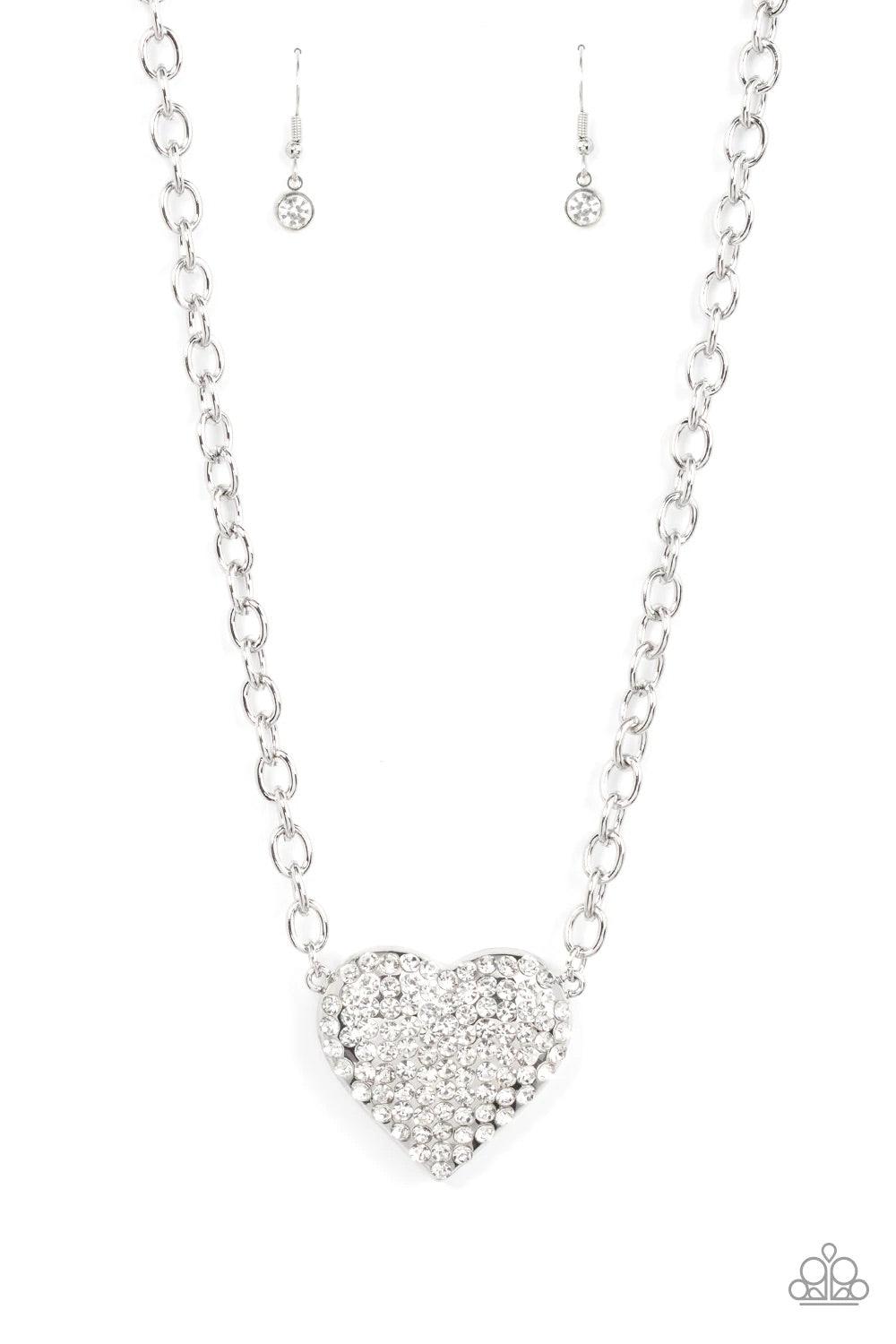 Paparazzi Accessories Heartbreakingly Blingy - White A dramatically oversized silver heart frame is encrusted in row after row of dazzling white rhinestones, resulting in heart-racing sparkle below the collar. Features an adjustable clasp closure. Sold as
