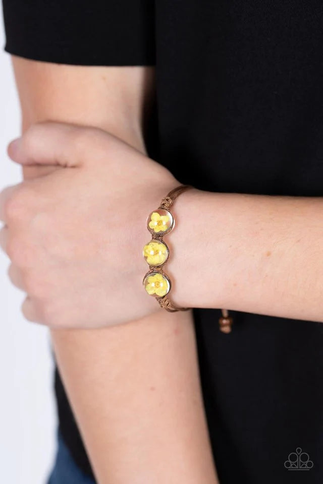Paparazzi Accessories Prairie Persuasion - Yellow Dainty yellow blossoms are encased inside of glassy beads that are knotted in place with brown cording around the wrist, resulting a naturally beautiful centerpiece. Features an adjustable sliding knot clo
