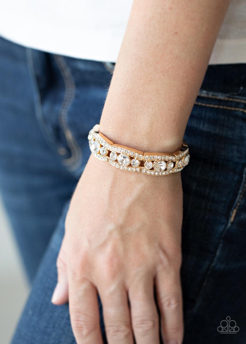 Paparazzi Accessories Easy On The ICE - Gold Rhinestone encrusted gold bars flank a dazzling trio of oversized white rhinestones, coalescing into a glittery frame. The sparkly frames are threaded along stretchy bands around the wrist, creating an irresist