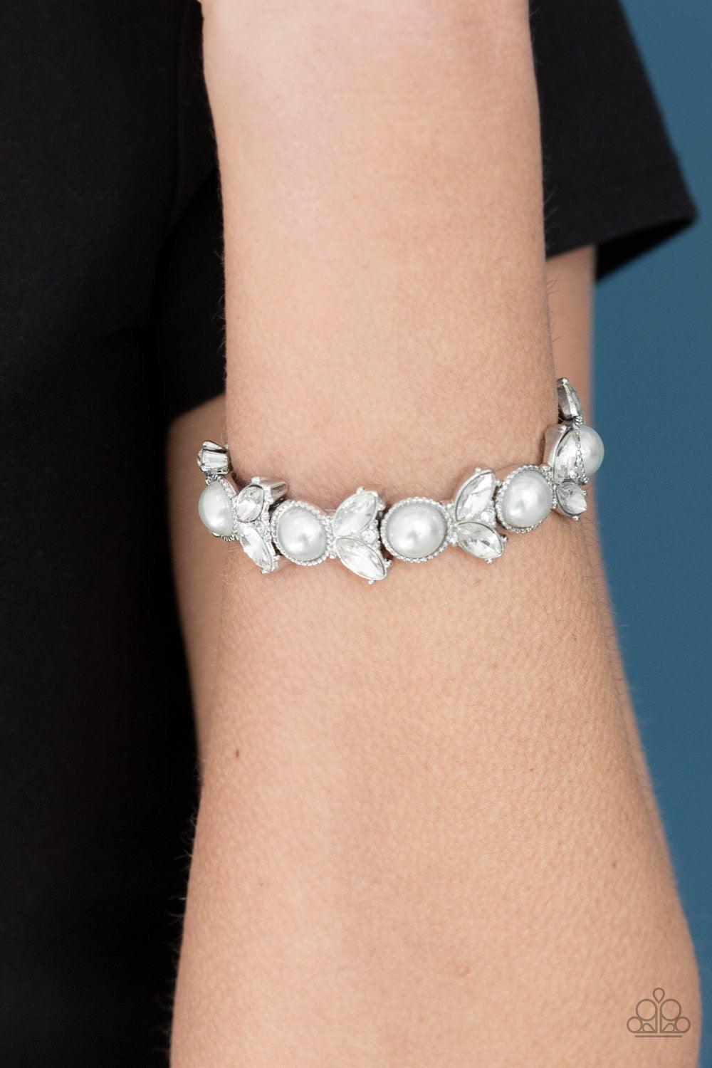 Paparazzi Accessories Opulent Oasis - White Encrusted in dazzling white rhinestones and an oversized white pearl, leafy silver frames are threaded along stretchy bands around the wrist for a timeless look. Sold as one individual bracelet. Jewelry