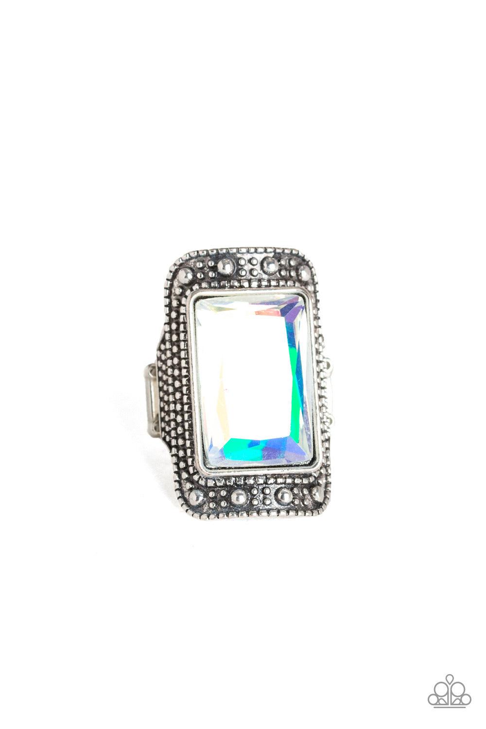 Paparazzi Accessories Very HEIR-descent ~White Featuring an iridescent oil spill finish, a dramatic emerald-cut gem is pressed into the center of a studded silver frame for a jaw-dropping look. Features a stretchy band for a flexible fit.
