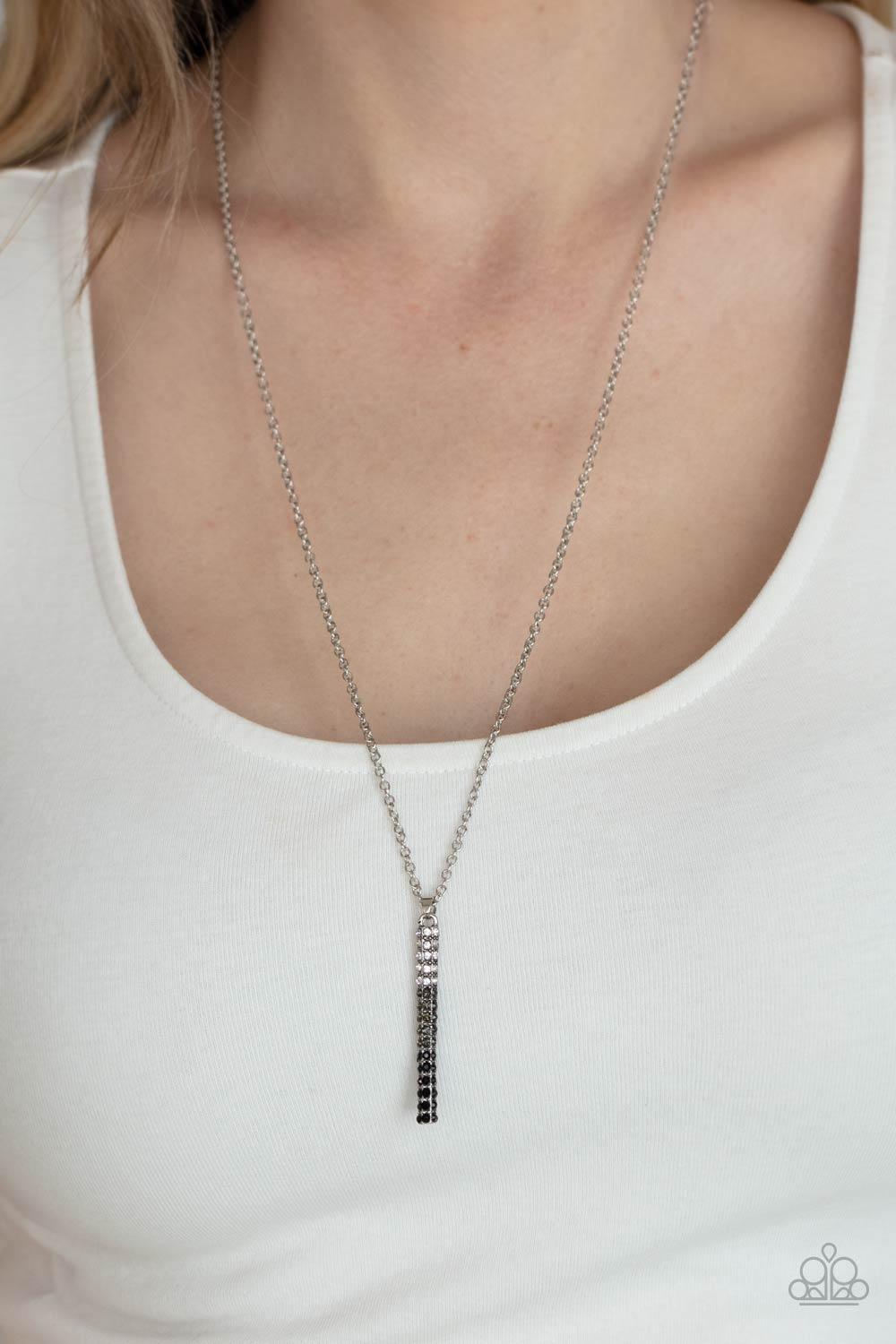 Paparazzi Accessories Tower of Transcendence - Black A sparkly collection of white, smoky, and black rhinestones are encrusted along a silver pendulum that swings along the bottom of a silver chain, creating a glittery ombre effect. Features an adjustable