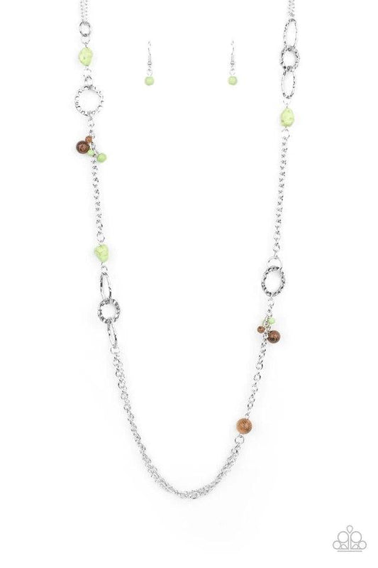 Paparazzi Accessories Sandstone Safari - Green A mismatched collection of brown wooden beads, green pebbles, hammered silver ovals, and dainty green stone beads haphazardly adorn sections of silver chain across the chest, creating an earthy seasonal flair