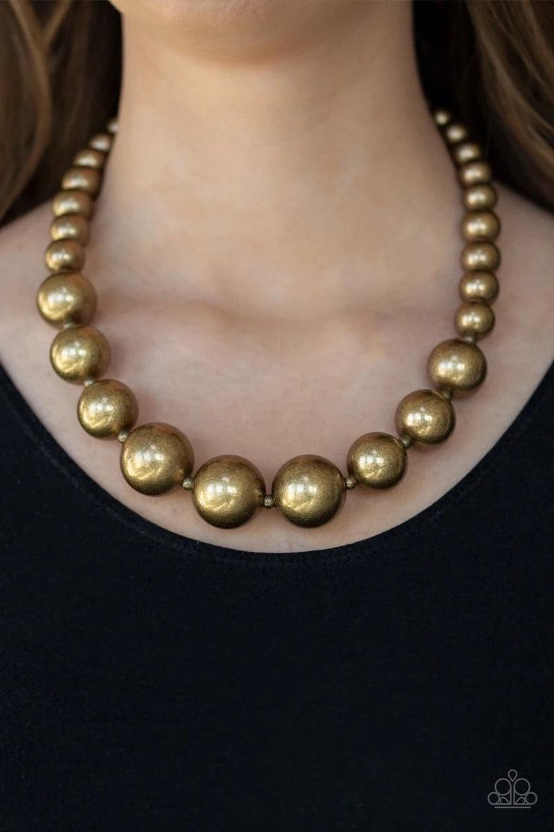 Paparazzi Accessories Living Up To Reputation - Brass A collection of bold brass beads are threaded along an invisible wire below the collar. The antiqued beads dramatically increase in size as they reach the center for an undeniable statement-making fini