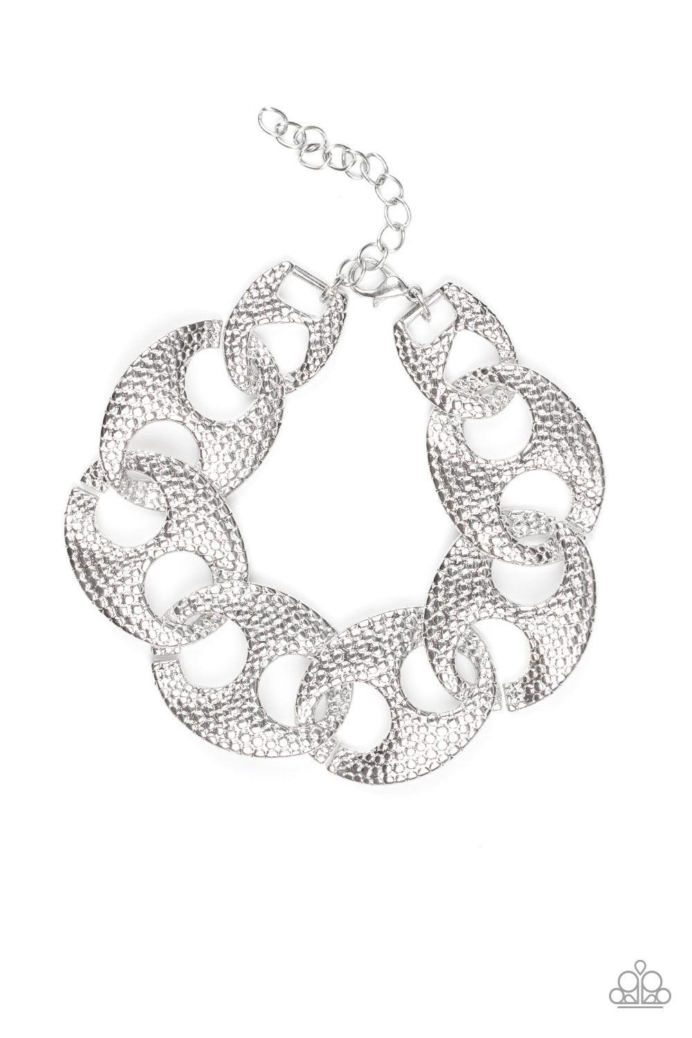 Paparazzi Accessories Casual Connoisseur - Silver Embossed in shimmery circular patterns, asymmetrical silver frames link across the wrist for a casually industrial look. Features an adjustable clasp closure. Jewelry