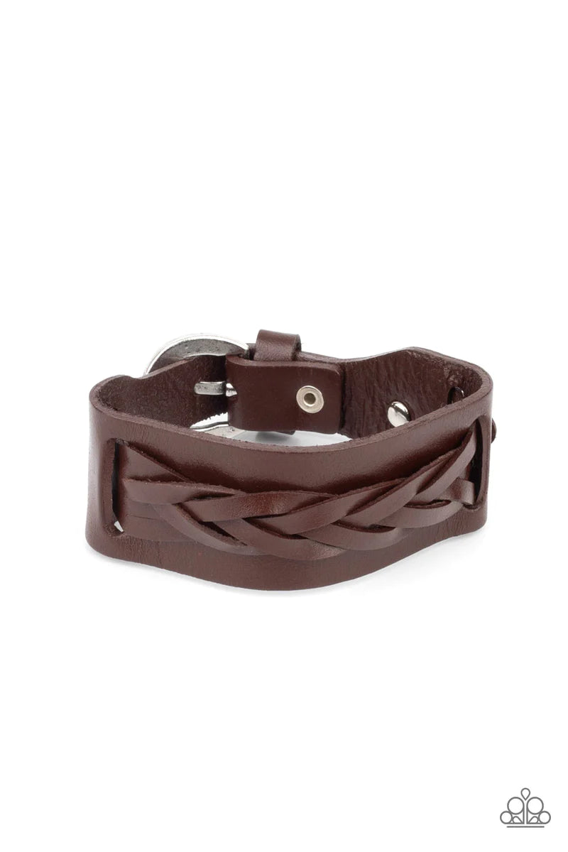 Paparazzi Accessories Practical Pioneer - Brown Braided strands of brown leather laces are studded in place across the front of a thick brown leather band with hammered silver studs, creating a rustic centerpiece around the wrist. Features an adjustable b