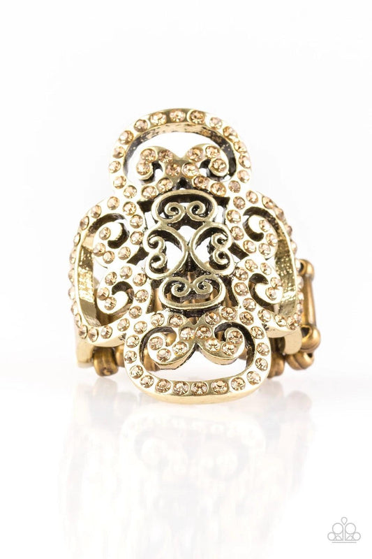 Paparazzi Accessories Regal Regalia - Brass Dainty topaz rhinestones are encrusted along a glistening brass frame radiating with regal filigree for a refined look. Features a stretchy band for a flexible fit. Sold as one individual ring. Jewelry