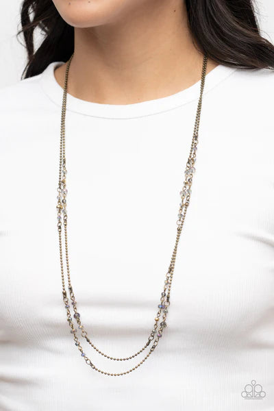 Paparazzi Accessories Petitely Prismatic - Brass Sections of aurum and iridescent crystal-like beads embellish strands of dainty brass beaded chains, resulting in prismatic layers across the chest. Features an adjustable clasp closure. Sold as one individ