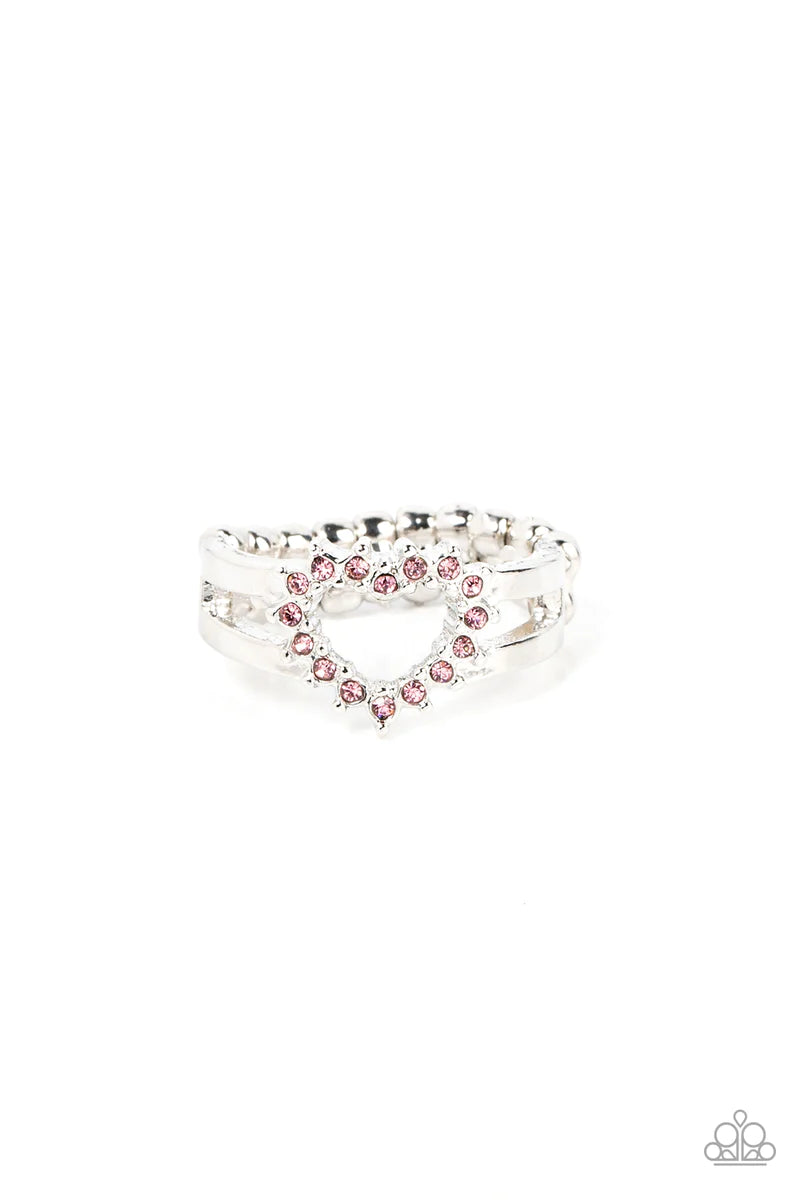 Paparazzi Accessories First Kisses - Pink Pink rhinestone pronged silver fittings coalesce into an airy heart frame atop the center of layered silver frames, resulting in a romantic centerpiece atop the finger. Features a dainty stretchy band for a flexib