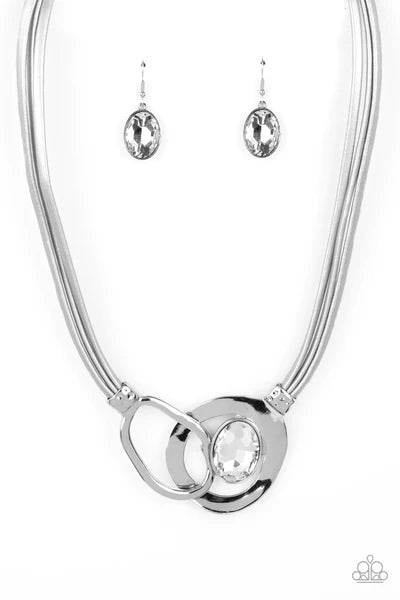 Paparazzi Accessories Californian Cowgirl - Silver Attached to shimmery strands of silver leather, a pair of oversized and warped silver links delicately overlaps into a contemporary centerpiece below the collar. An exaggerated white gem asymmetrically em