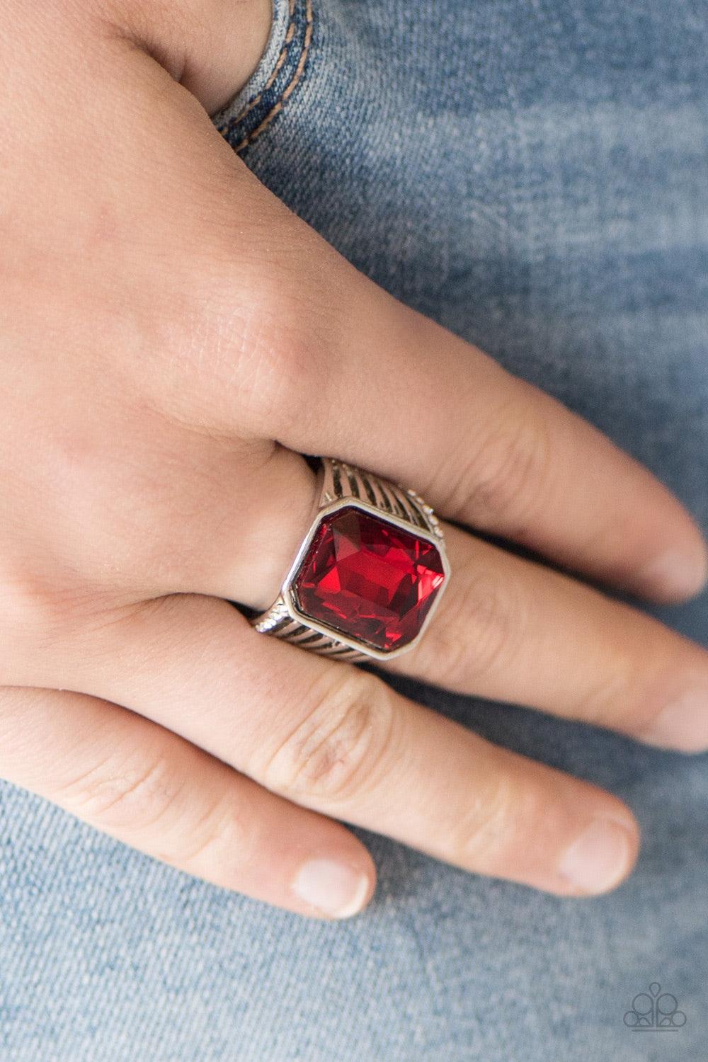 Paparazzi Accessories Make Way For The Champ - Red Featuring a regal emerald style cut, a faceted red gem is pressed into an airy band, creating a champion shimmer. Features a stretchy band for a flexible fit. Jewelry