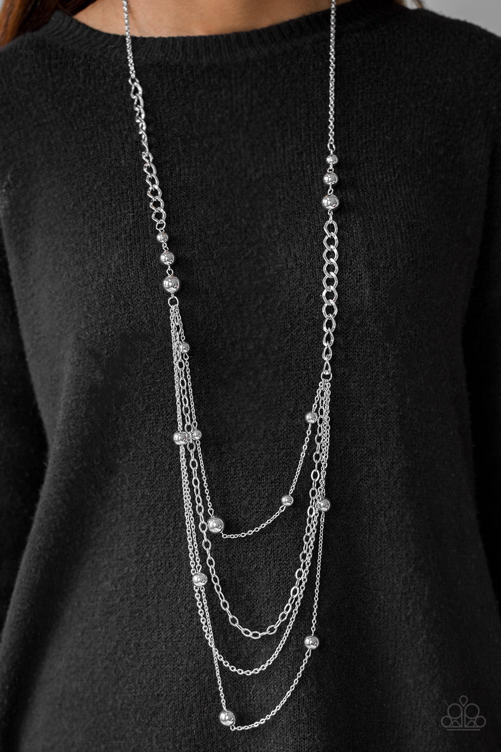 Paparazzi Accessories Boss Shimmer - Silver A mishmash of classic silver beading and bold chain links trickle along shimmery silver chains, creating an asymmetrically layered look. Features an adjustable clasp closure. Sold as one individual necklace. Inc