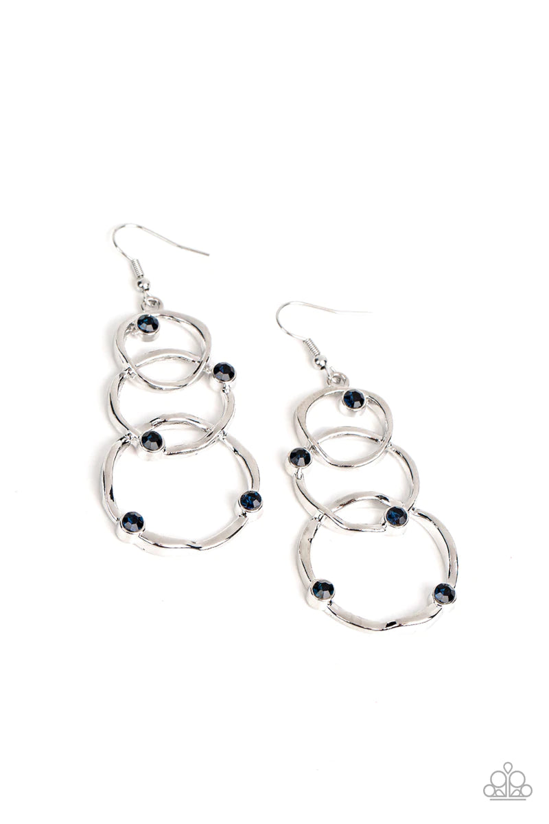 Paparazzi Accessories Revolving Radiance - Blue A sprinkling of glittery blue rhinestones floats across a trio of wavy silver circles that graduate in size as they interlock into a glamorously luminous lure. Earring attaches to a standard fishhook fitting