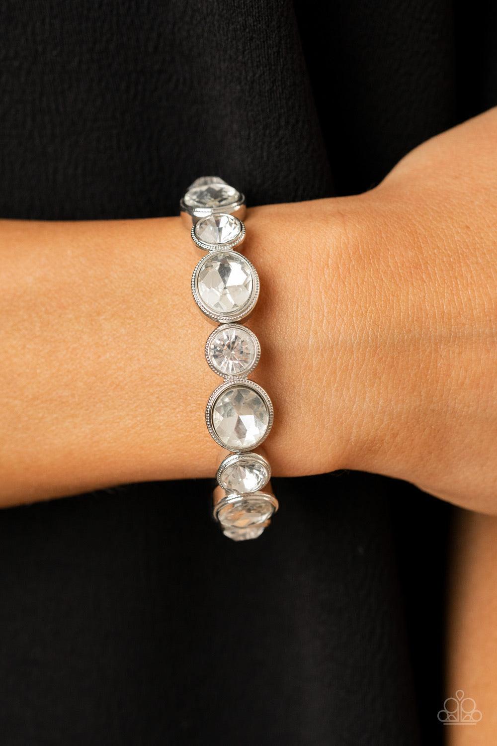 Paparazzi Accessories Still GLOWING Strong - White Encased in sleek silver frames, oval and round white rhinestones alternate along a stretchy band around the wrist for a timeless look. Sold as one individual bracelet. Jewelry