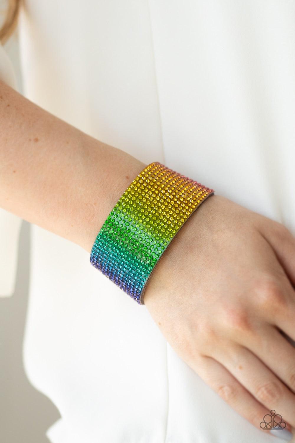Paparazzi Accessories Fade Out - Multi Row after row of glassy rhinestones gradually fade from pink, purple, blue, green, and yellow across the front of a thick gray suede band, creating a trendy rainbow ombre. Features an adjustable snap closure. Jewelry