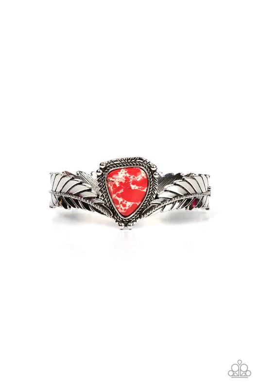Paparazzi Accessories Desert Roost - Red A twisted metal bar lines the center of an elongated silver feather as it curves into a rustic cuff. Featuring a studded and textured silver frame, an asymmetrical red stone is balanced between the ends of the silv