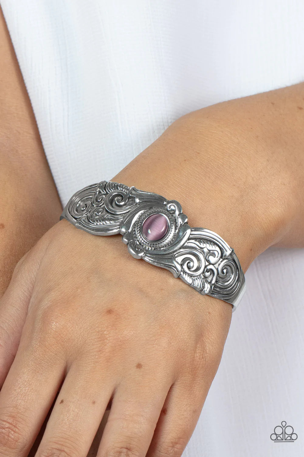 Paparazzi Accessories Glowing Enchantment - Purple Embossed in vine-like filigree patterns, an ornately scalloped silver cuff is adorned with a glassy purple cat's eye center for an ethereal finish. Sold as one individual bracelet. Bracelets