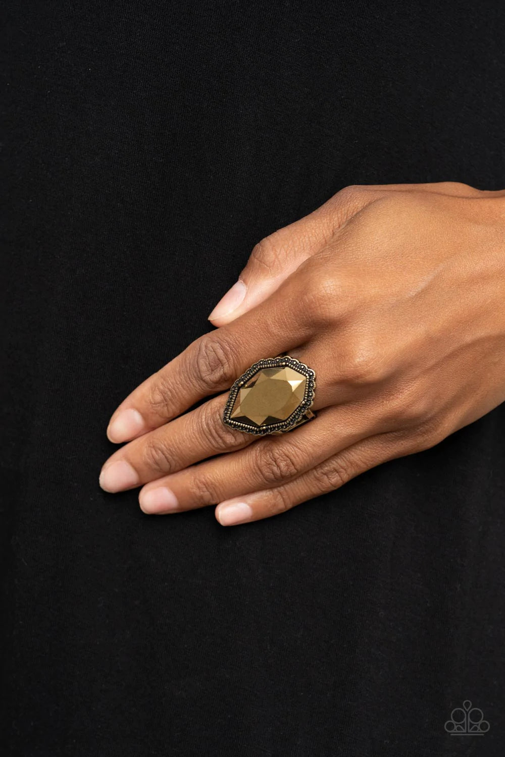 Paparazzi Accessories Avant-GRANDEUR - Brass An oversized faceted aurum gem is nestled inside a scalloped brass frame radiating with studded textures, resulting in a radiant centerpiece atop the finger. Features a stretchy band for a flexible fit. Sold as