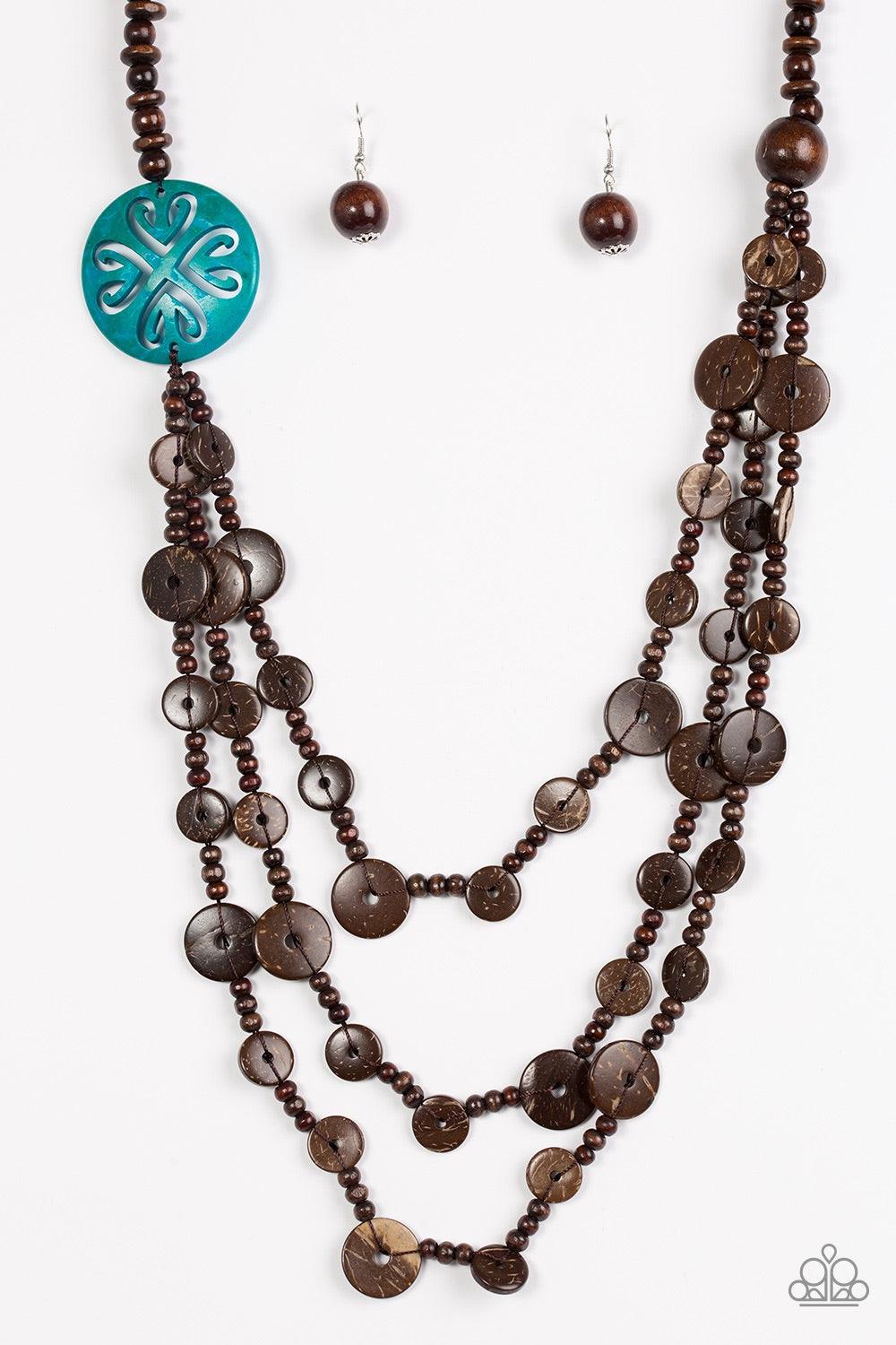 Paparazzi Accessories Jungle Jive - Blue Mismatched brown wooden beads are threaded along a shiny brown string, creating summery layers across the chest. Featuring a whimsical floral pattern, a dramatic blue wooden bead adorns one side for a seasonal fini