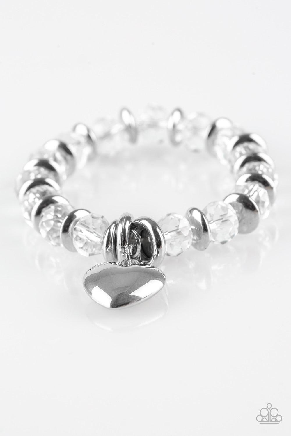 Paparazzi Accessories Need I Say AMOUR? - White Sparkling crystal-like beads and shimmery silver accents are threaded along a stretchy band. An oversized silver heart charm swings from the wrist for a whimsical finish. Sold as one individual bracelet. Jew