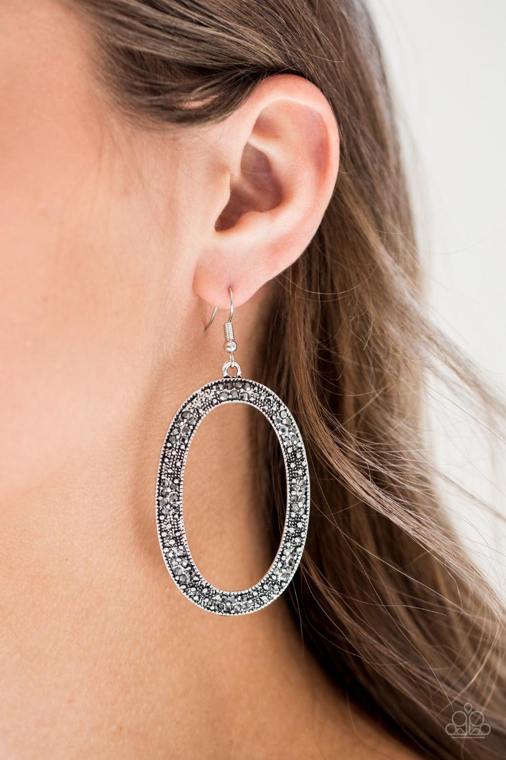 Paparazzi Accessories Rhinestone Rebel - Silver Glistening silver studs and glittery hematite rhinestones are sprinkled along an ornate silver hoop for an edgy look. Earring attaches to a standard fishhook fitting. Jewelry