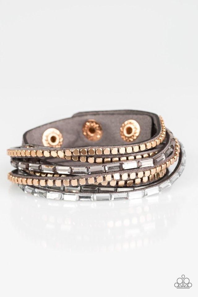Paparazzi Accessories This Time With Attitude - Silver Smoky and white emerald cut rhinestones and flat gold cube beads are encrusted along strands of gray suede for a sassy look. The elongated band double wraps around the wrist for a fierce one-of-a-kind