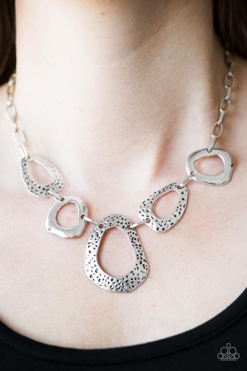 Paparazzi Accessories Very CAVE-alier ~Silver Delicately hammered and dotted with antiqued shimmer, asymmetrical silver frames link below the collar in a handcrafted, artisanal style. Features an adjustable clasp closure. Sold as one individual necklace.