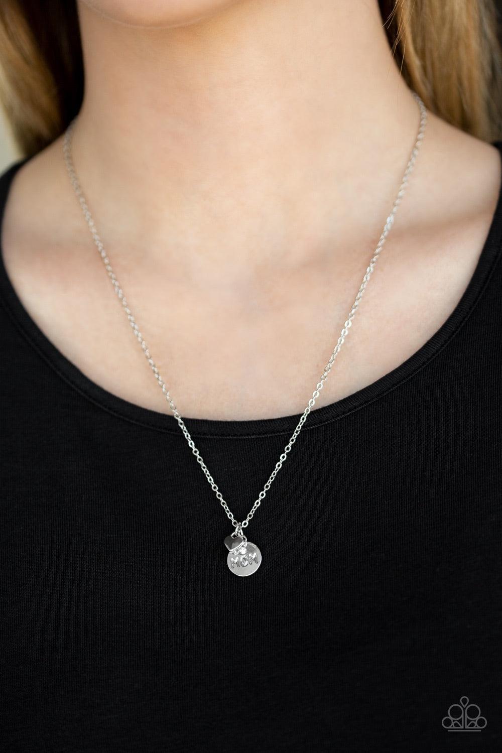 Paparazzi Accessories Worlds Best Mom - White Dotted with a dainty white rhinestone, a shimmery silver disc stamped in the word, "mom", joins a dainty silver heart below the collar for a whimsical look. Features an adjustable clasp closure. Jewelry