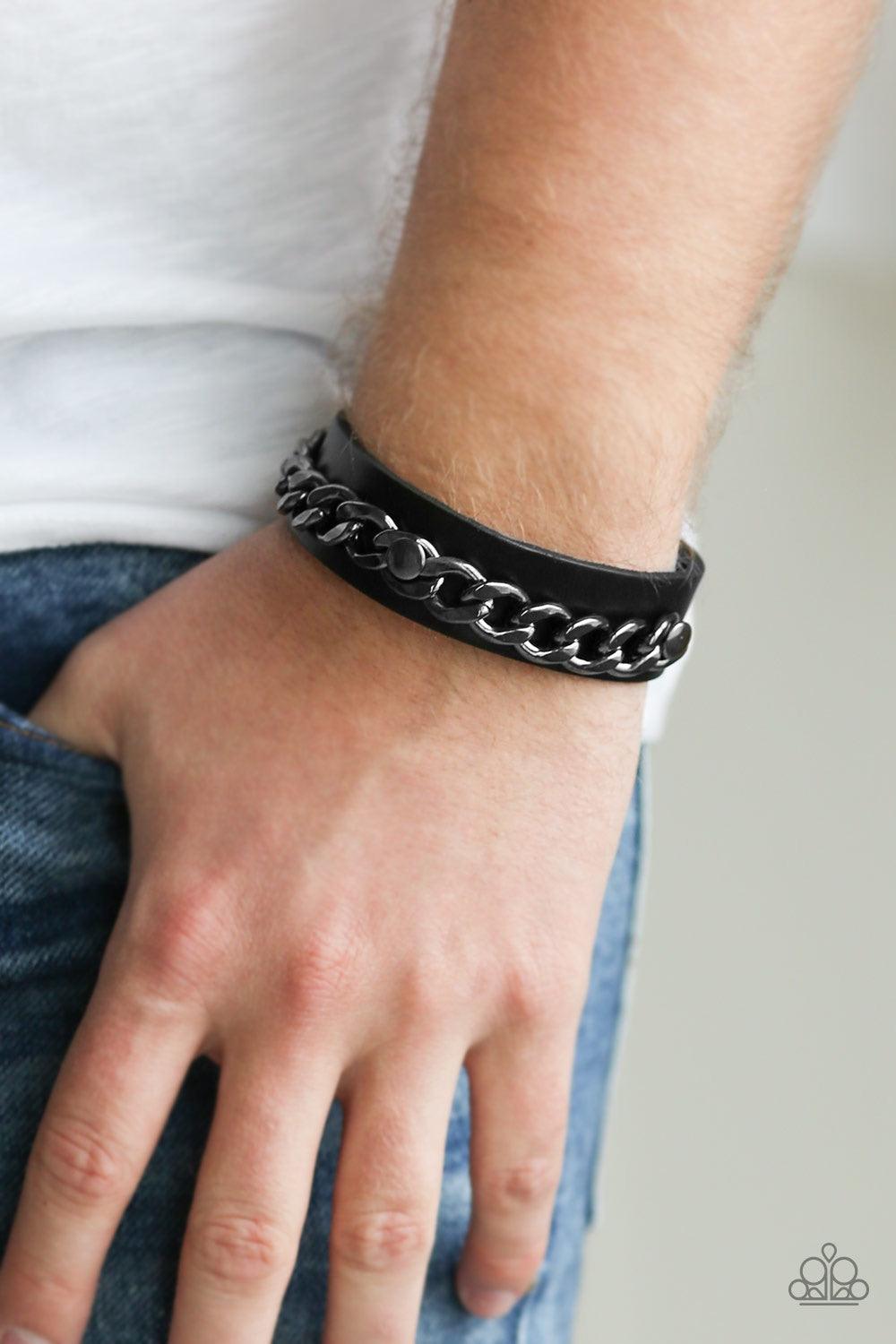 Paparazzi Accessories Be The CHAINage - Black A glistening gunmetal chain is studded in place across the front of a black leather band for an urban look. Features an adjustable snap closure. Jewelry