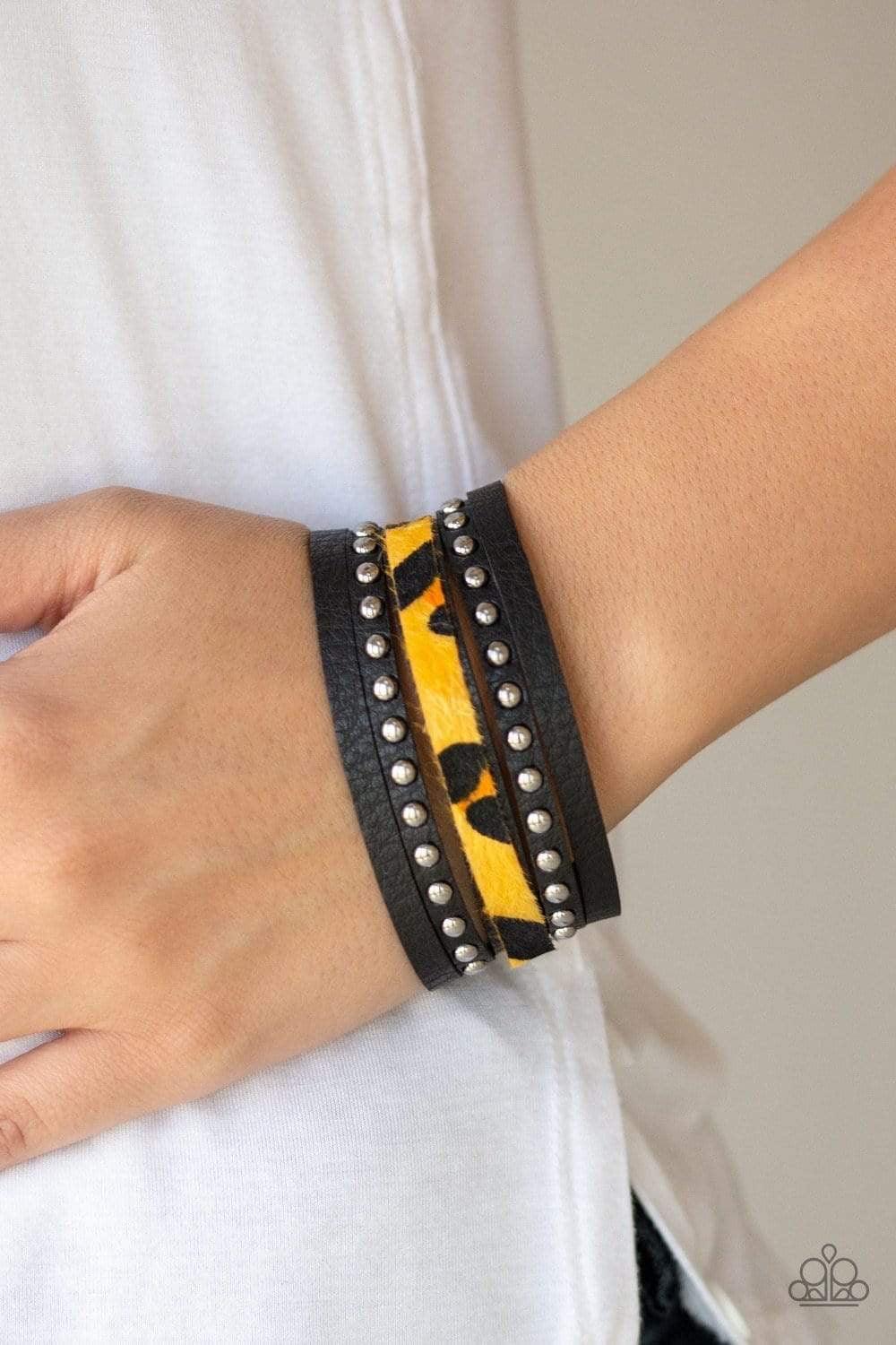 Paparazzi Accessories Born to be Wildcat -Yellow A thick band of black leather has been spliced into layered bands that have been studded and printed in a fuzzy cheetah print for a wild look. Features an adjustable snap closure. Sold as one individual bra