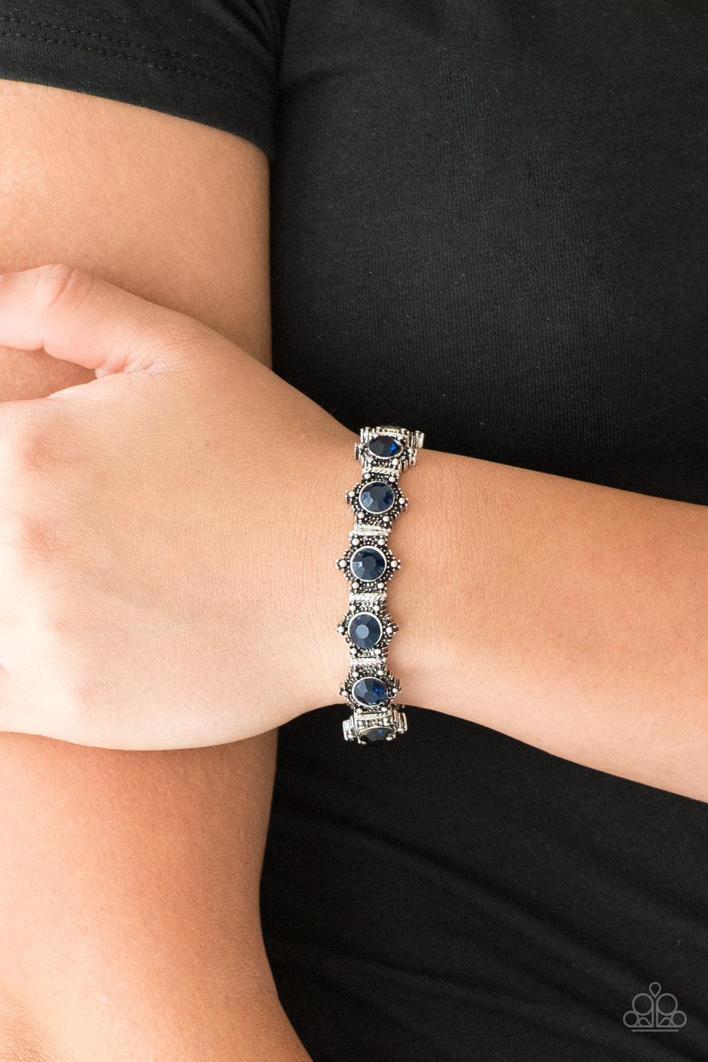 Paparazzi Accessories Strut Your Stuff - Blue Featuring glittery blue rhinestone centers, ornate silver frames are threaded along stretchy bands, linking across the wrist for a refined look. Jewelry